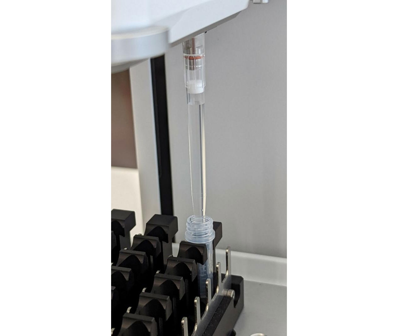 A close-up view of the ASSIST PLUS pipetting robot aliquoting reagent from a manufacturer’s tube with the D-ONE pipetting module.
