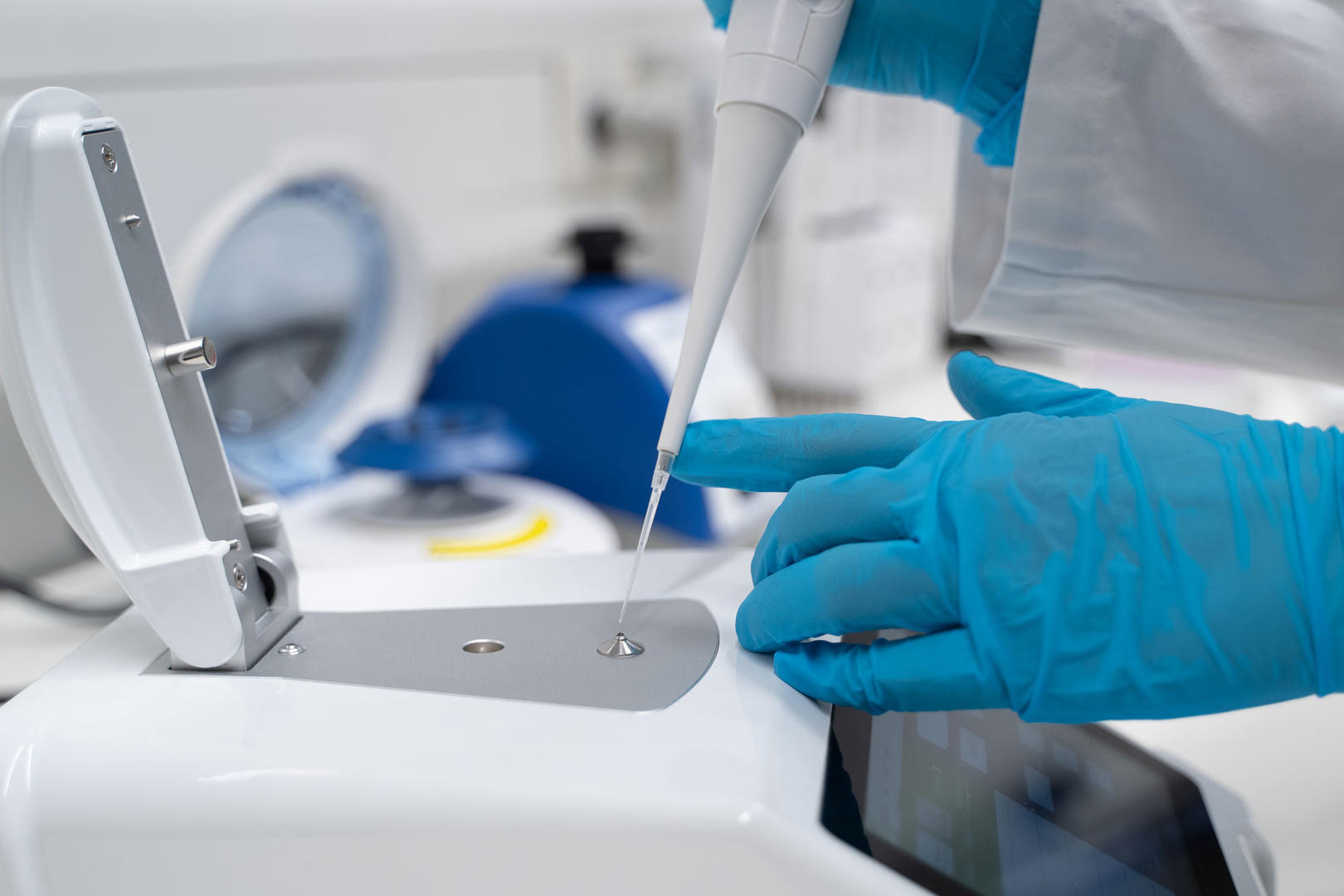 Scientist pipetting a droplet of liquid onto a microspectrophotometer for DNA quantification