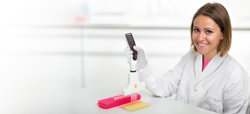Scientist using a VOYAGER adjustable tip spacing pipette to transfer liquid from Eppendorf tubes to 96 well plate.