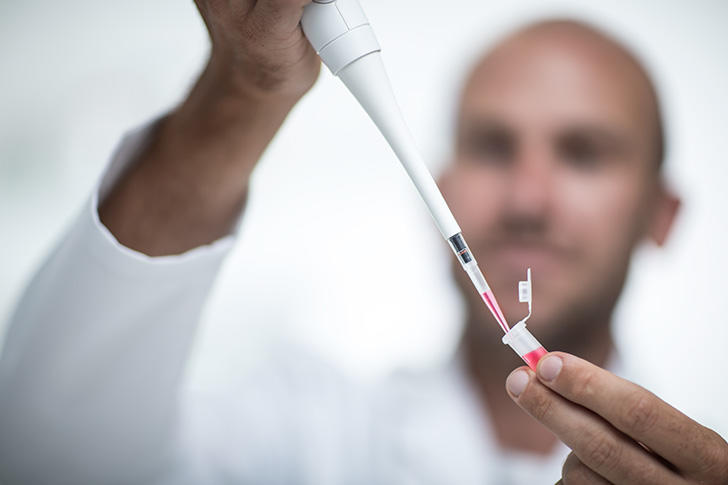 Scientist using a single channel EVOLVE manual pipette to dispense liquid into a PCR tube