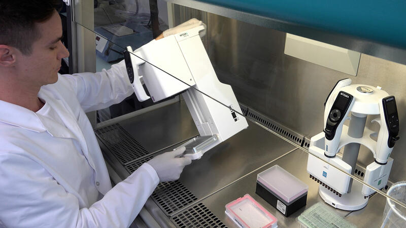 Scientist placing a MINI 96 pipette in a laminar flow cabinet